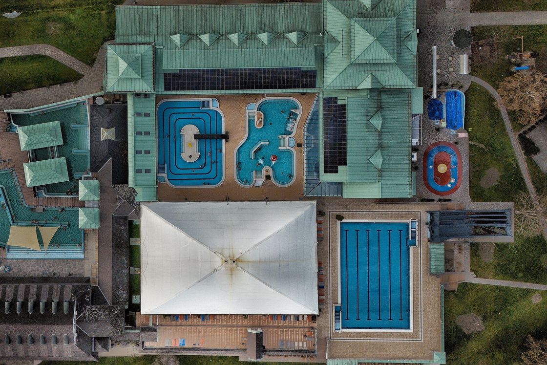 Aerial view of a municipal aquatic centre, showing its pools, plant and surrounding grounds.